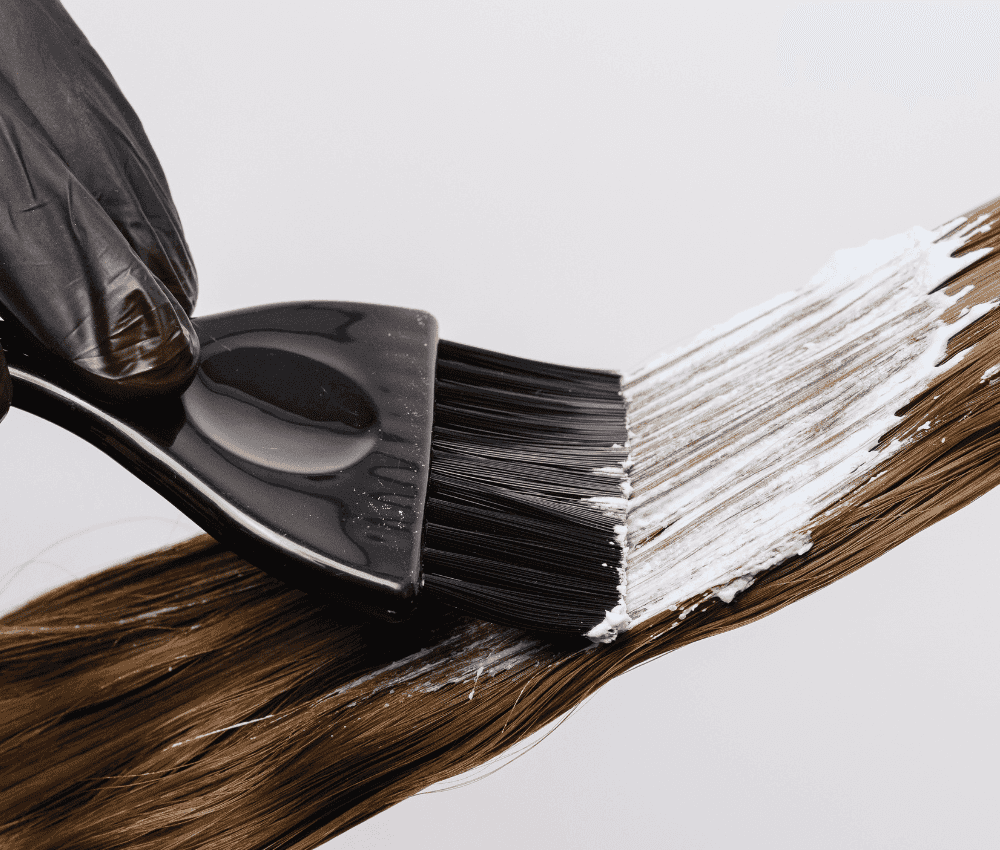 Applying hair dye with a brush on strands of hair.