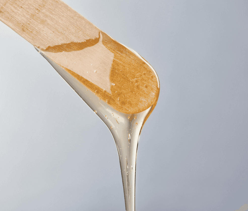 A close-up of honey dripping from a wooden dipper.